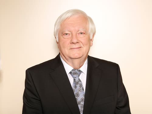 Wamser-Team: Wamser G Herr G. Wamser: Eine Person trägt einen schwarzen Anzug, ein weißes Hemd und eine gemusterte Krawatte.
