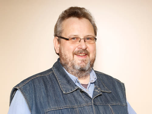 Wamser-Team: Weiss Herr A. Weiss: Eine Person trägt eine Bril-le, ein blaues Hemd und eine Jeansjacke.